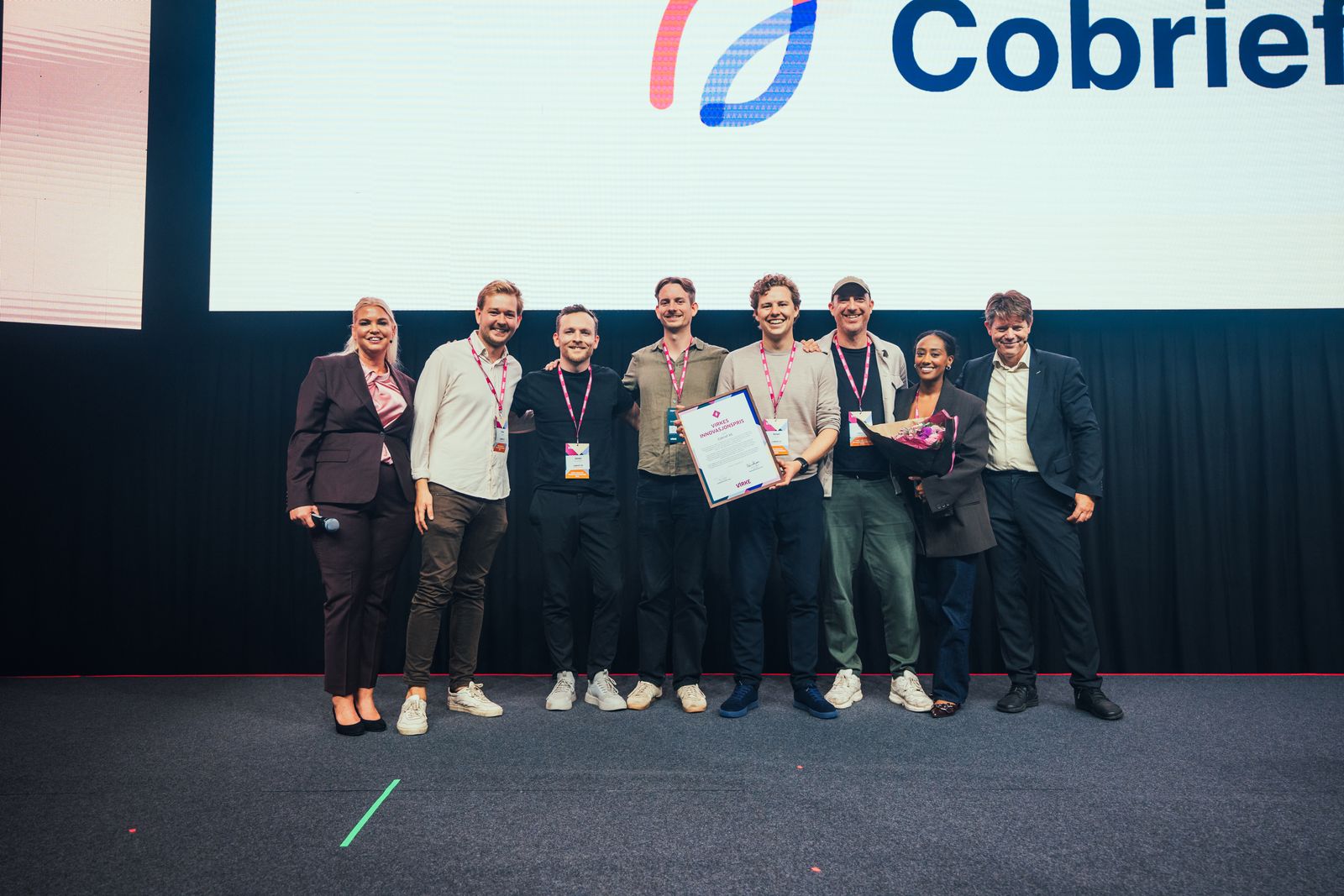 Het Cobrief-team met diploma en bloemen samen met Virke na de prijsuitreiking